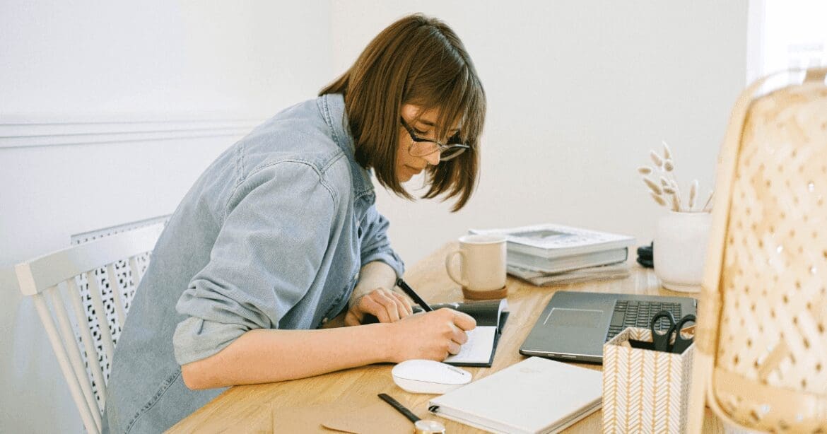 Woman brainstorming ideas for her blog, jotting down notes in a notebook for content creation