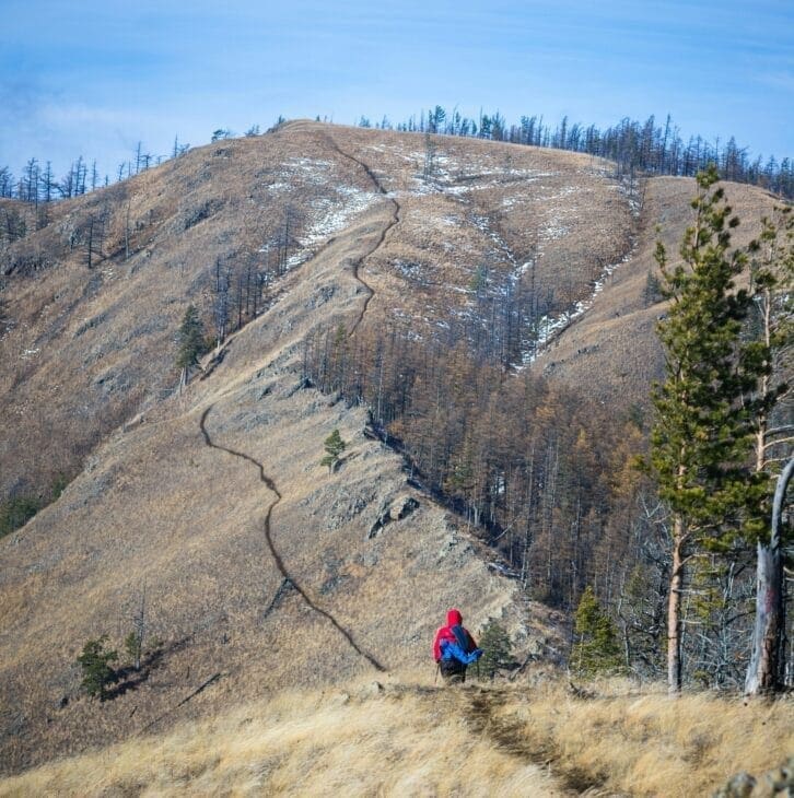 Hiker climbing a winding mountain path, symbolizing perseverance and motivation