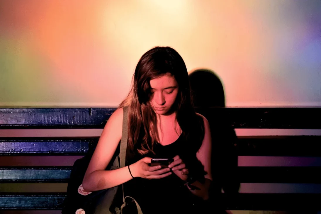 Young woman looking worried while checking her phone, reflecting the impact of online conversations on mental health.