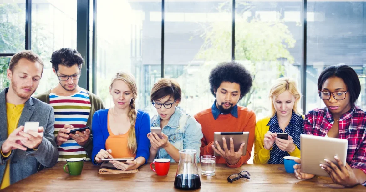 A diverse group of people holding various gadgets, including smartphones, tablets, and laptops.