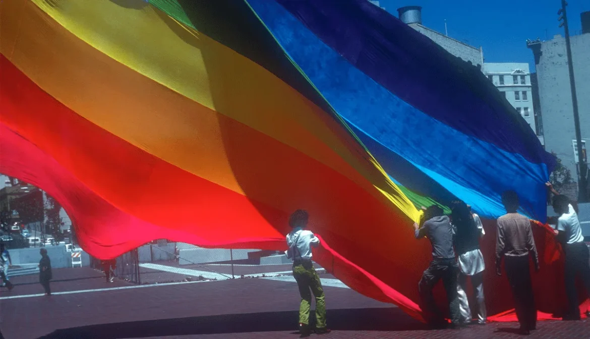 A group of people holding a rainbow flag, representing LGBTQ+ pride and social movements representing the symbolic meaning of colors