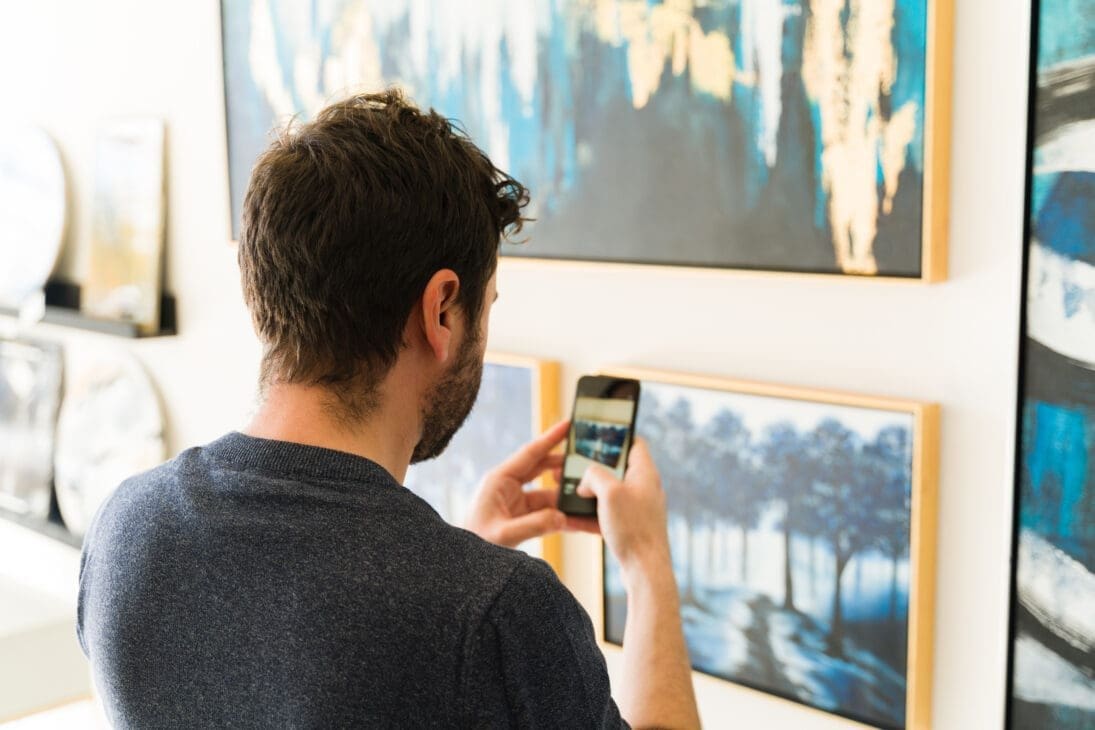 Man taking a photo of artwork in a museum to capture and reflect on the experience.