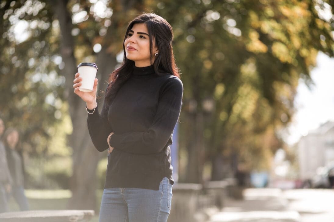 Young woman taking a short walk with coffee to recharge during a workday.