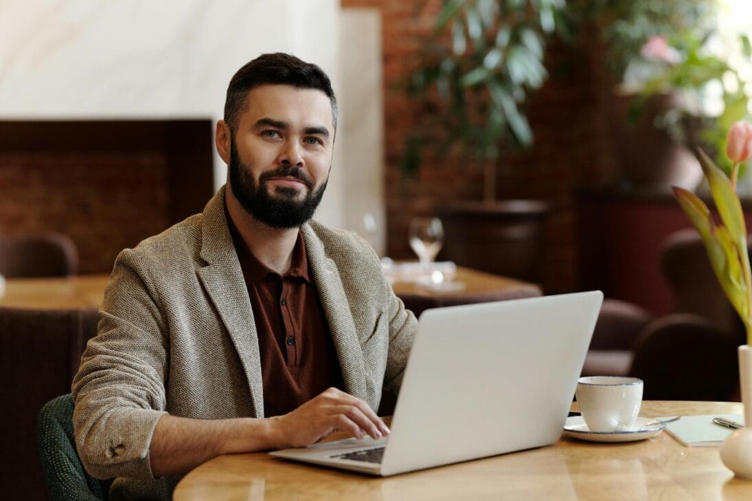 oung professional working with coffee cup and laptop between café stops.