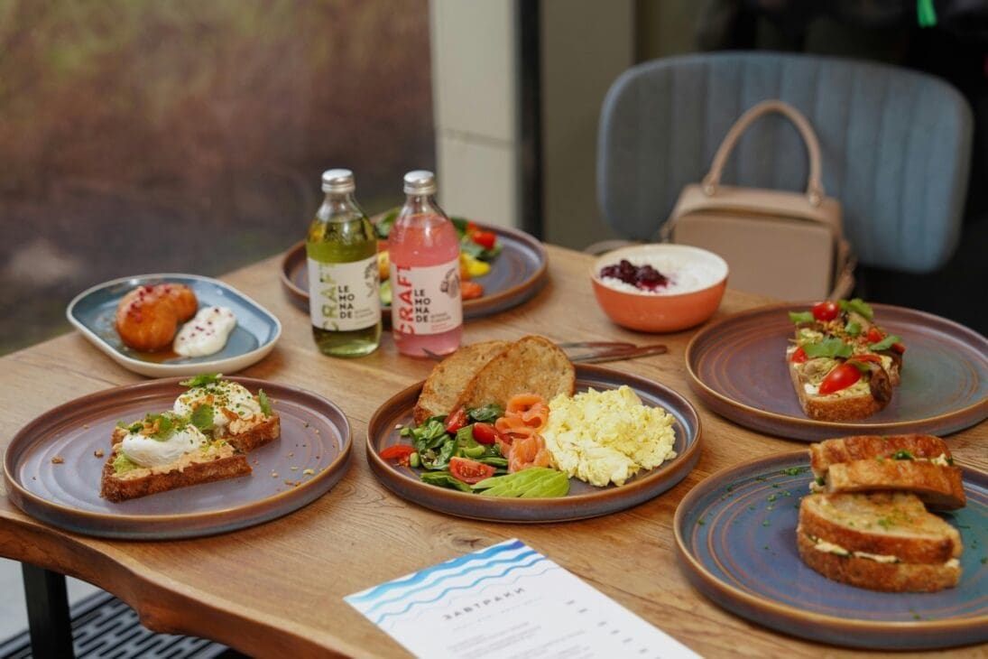 Healthy breakfast with avocado toast, Greek yogurt, and drinks on a wooden table