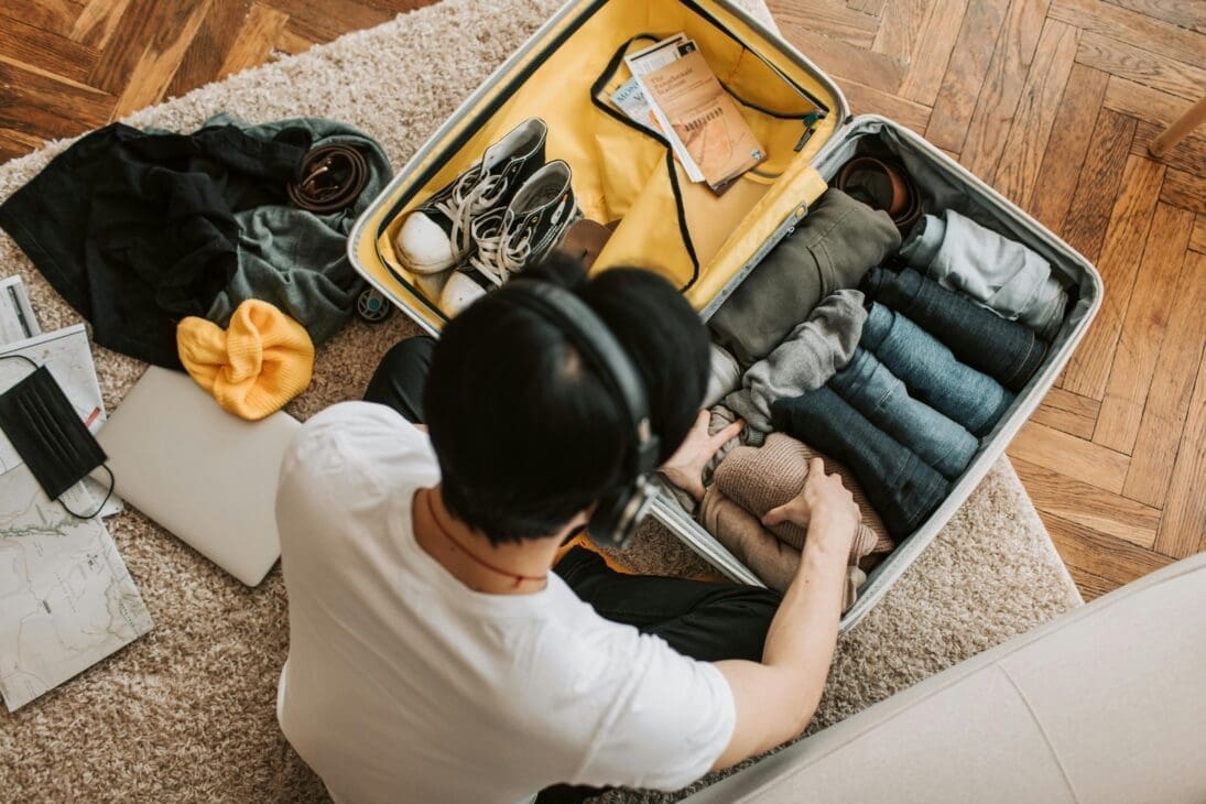 Neatly organized suitcase with rolled clothes, packing cubes, shoes, and a compact travel steamer for efficient packing.