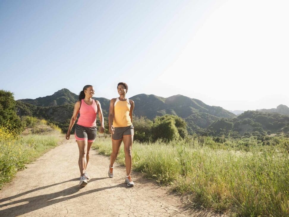 Two girls walking with proper posture head level, shoulders relaxed, and spine aligned demonstrating healthy walking form.